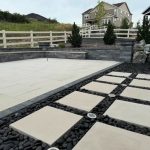 Modern patio with large beige tiles and black pebbles