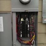 Open electrical panel showing wires and the circuit board, with breakers in place