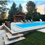 Sunset view of a backyard with a pool, surrounded by trees