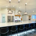 elegant kitchen with droplights and bar with chairs