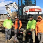 A group of workers in front of a Bobcat E88 compact excavator