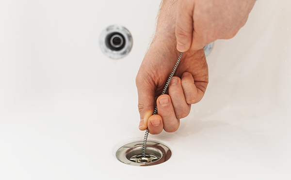 person inserting spring wire in the drain