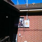 Electrical box mounted on the exterior wall of a home, with wires connected for power distribution