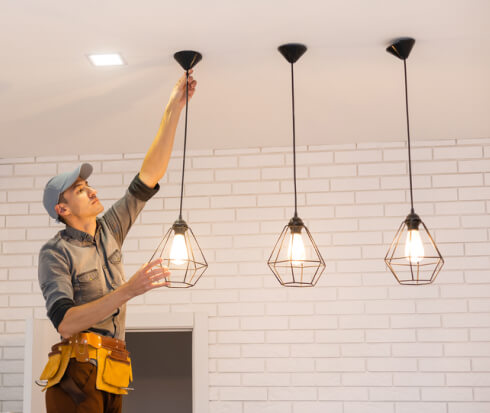 Electrician fixing pendant lamps in Denver apartment