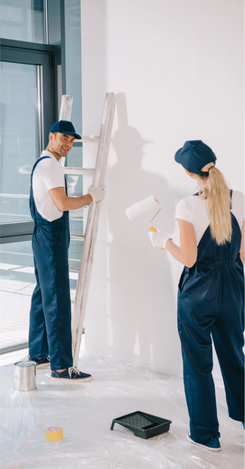 handsome-painter-standing-ladder-while-pretty-colleague-holding-paint-roller