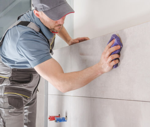 Bathroom Remodeling worker cleaning bathroom wall with sponge