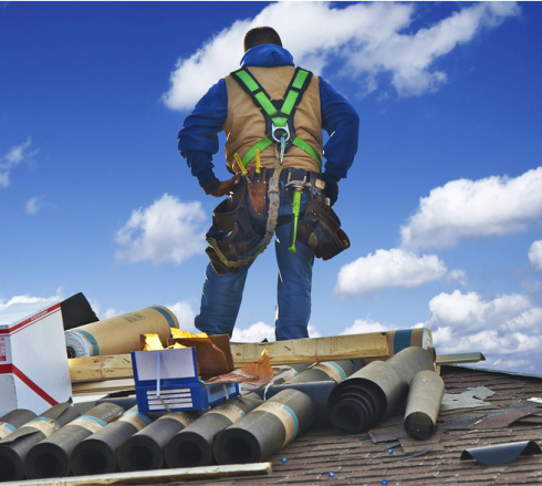 worker standing on a roof to check area while repairs are ongoing