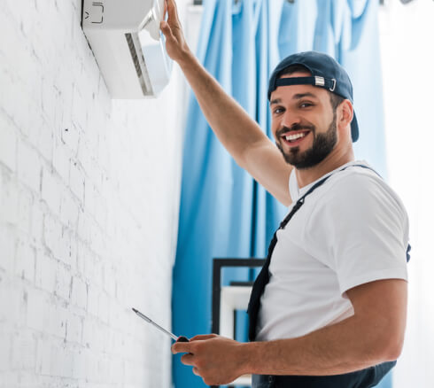 Smiling HVAC technician while repairing air conditioner