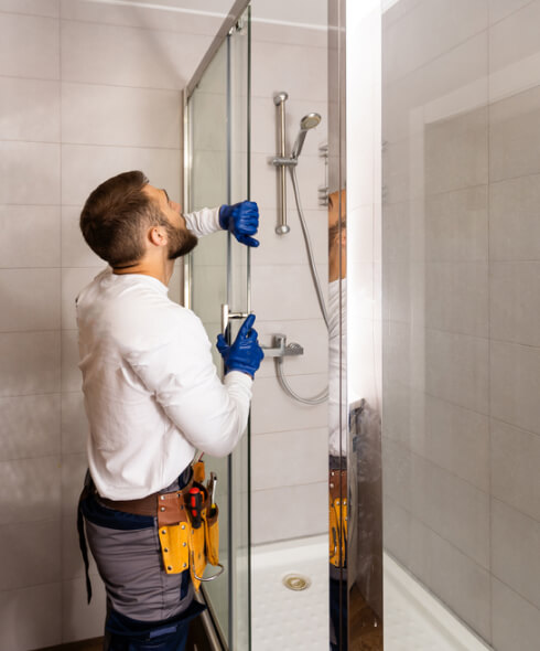 Bathroom Remodeling worker installing glass walls of shower enclosure