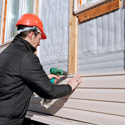 worker installing siding on the exterior of a house