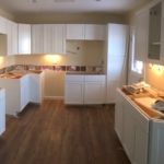 A modern kitchen with white cabinetry and a light-colored countertop