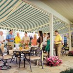 people gather at the poolside covered by awnings