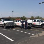 a parking lot with several white trucks and SUVs