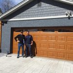 two people standing in front of a residential garage door