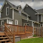 House featuring a prominent wooden deck and stairs leading to a backyard area