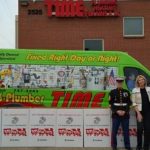 Time Plumbing staff standing at storefront with the service car and large boxes