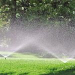 water sprinklers spraying water on a grassy yard